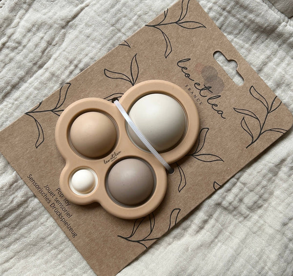 Jouet sensoriel Pop It Léo et Léa en silicone beige avec quatre bulles à presser