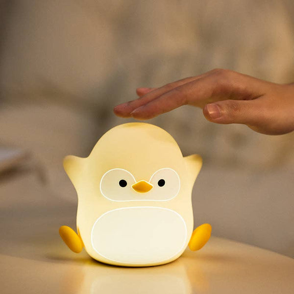 Veilleuse enfant pingouin en silicone blanc et jaune allumée avec lumière chaude